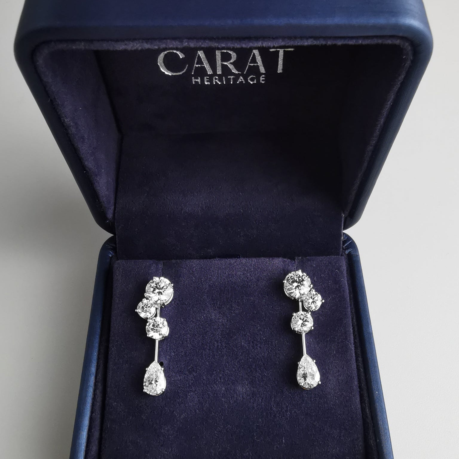 Pair of silver earrings in a 'Carat Heritage' jewelry box.