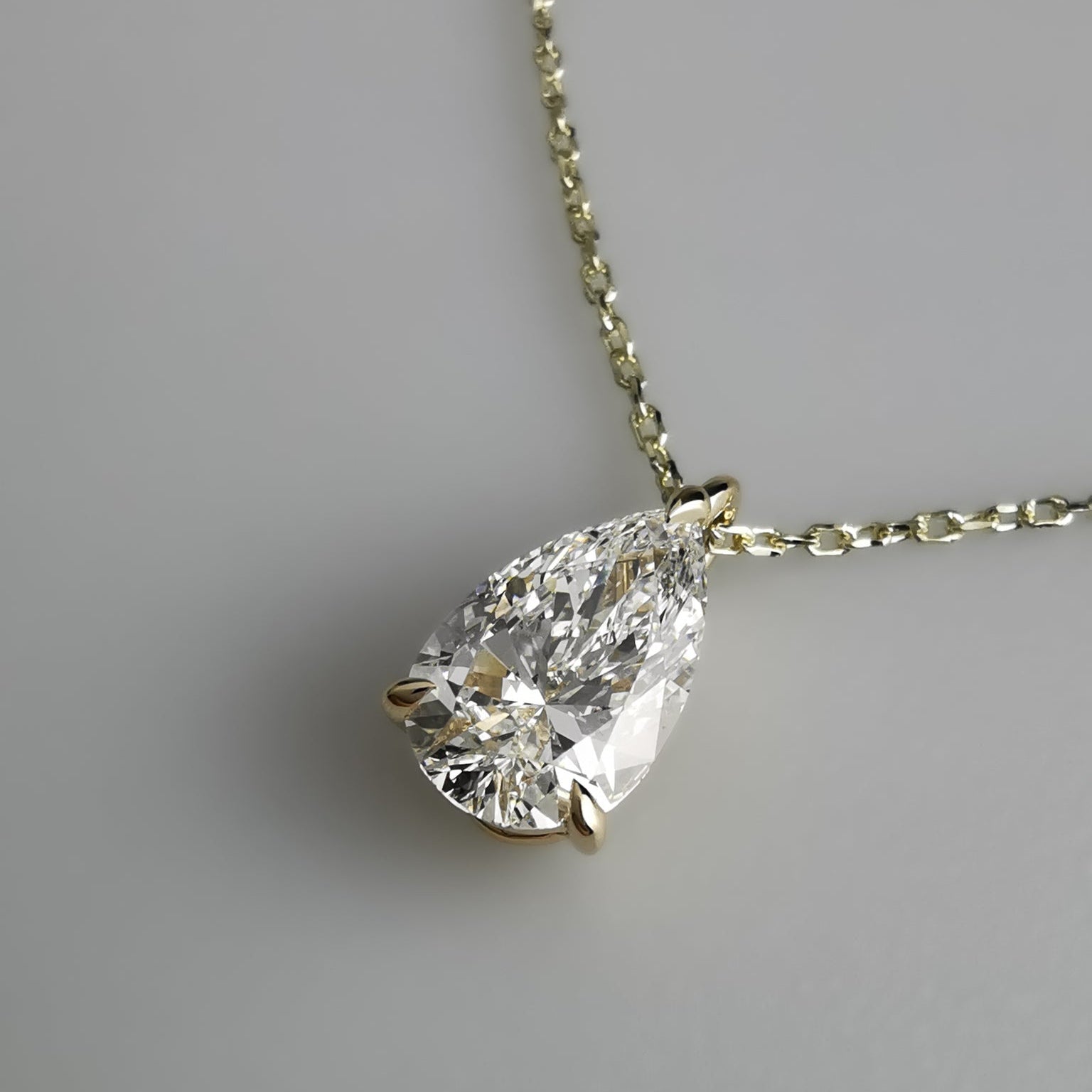 A pear-cut diamond pendant in a gold solitaire setting on a delicate gold chain