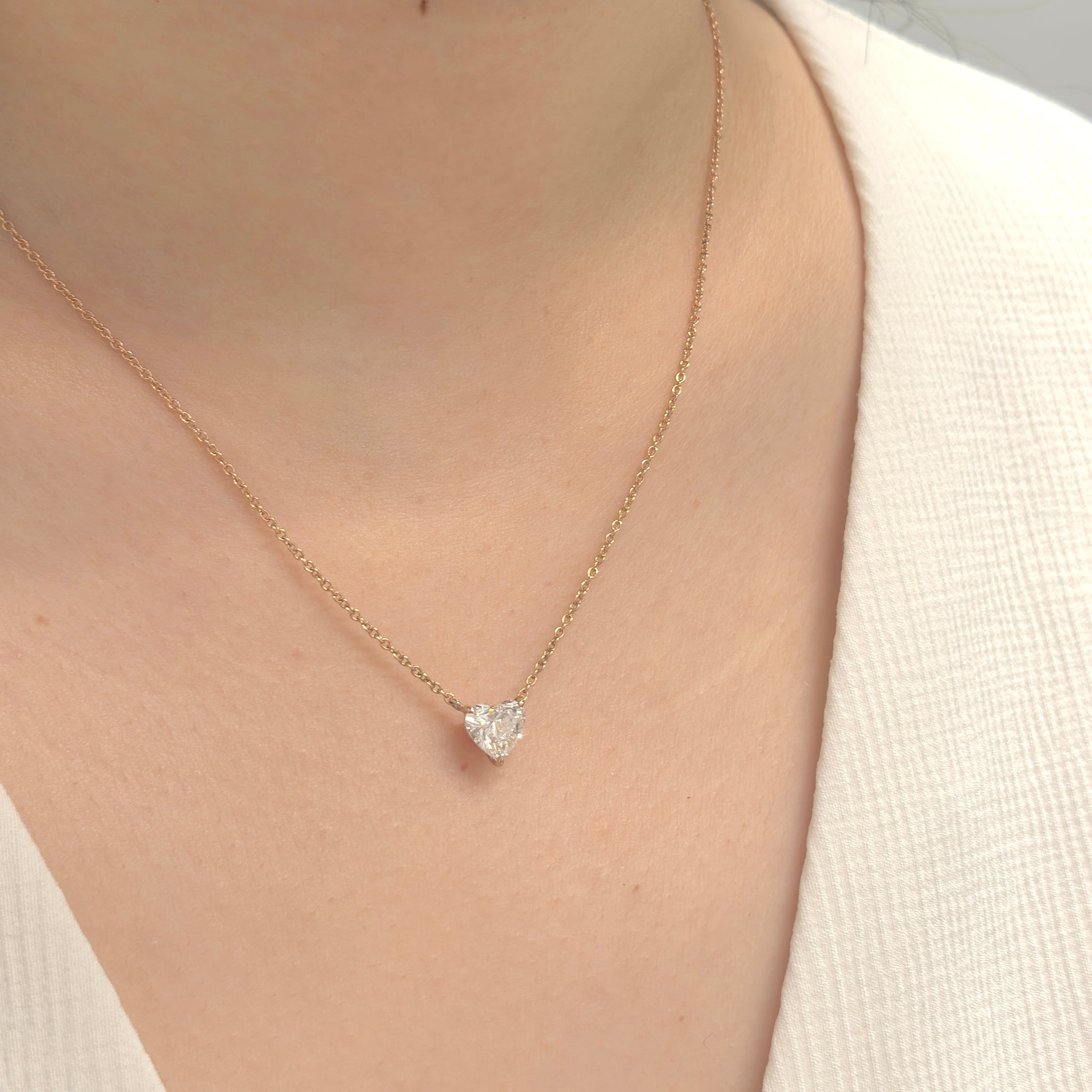 Gold necklace with a heart-shaped pendant worn by a person