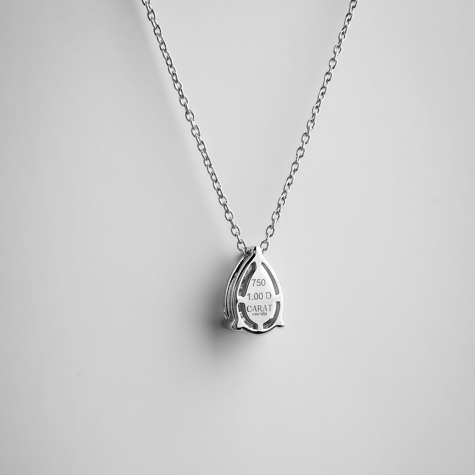 Silver teardrop-shaped pendant on a chain against a gray background